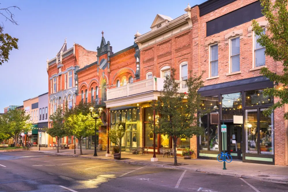 A scenic view of a charming downtown street with historic brick buildings, sidewalk cafes, and trees.