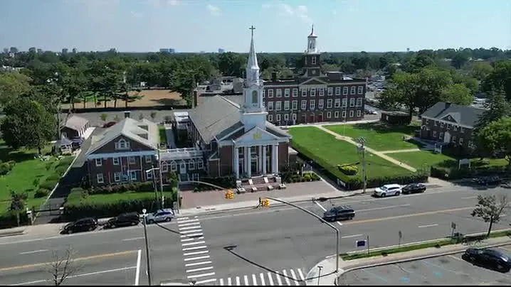Aerial view of a church with a tall steeple and a large building behind it