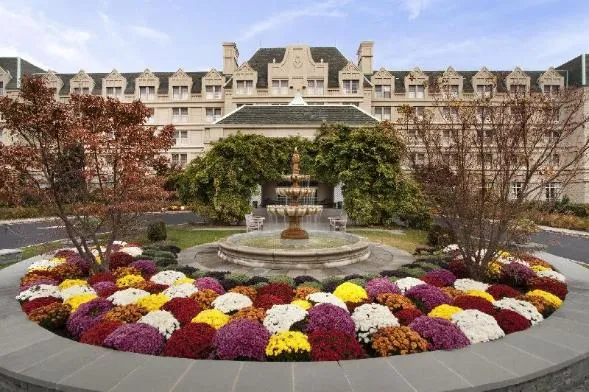 Beautiful floral display surrounding a fountain in front of a large building.